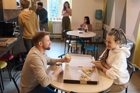 il y a plusieurs personne qui se parle ou mange dont deux au premier plan
