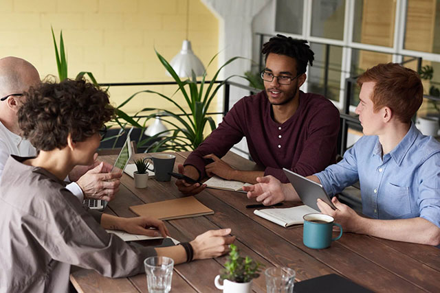 quatre personne qui travail de bonne humeur. Cela représente le coworking.